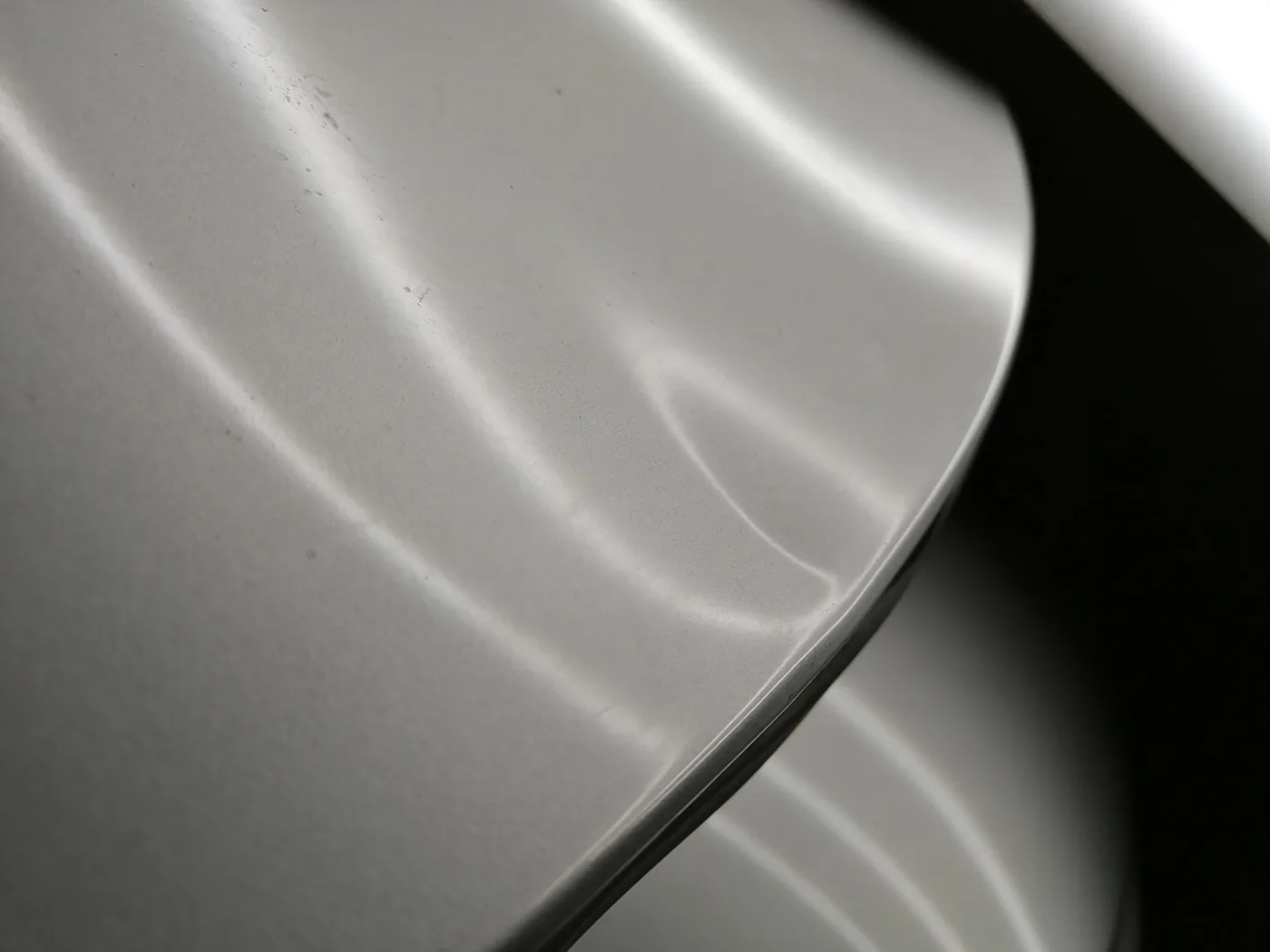 Silver vehicle panel with a crease dent, before repair